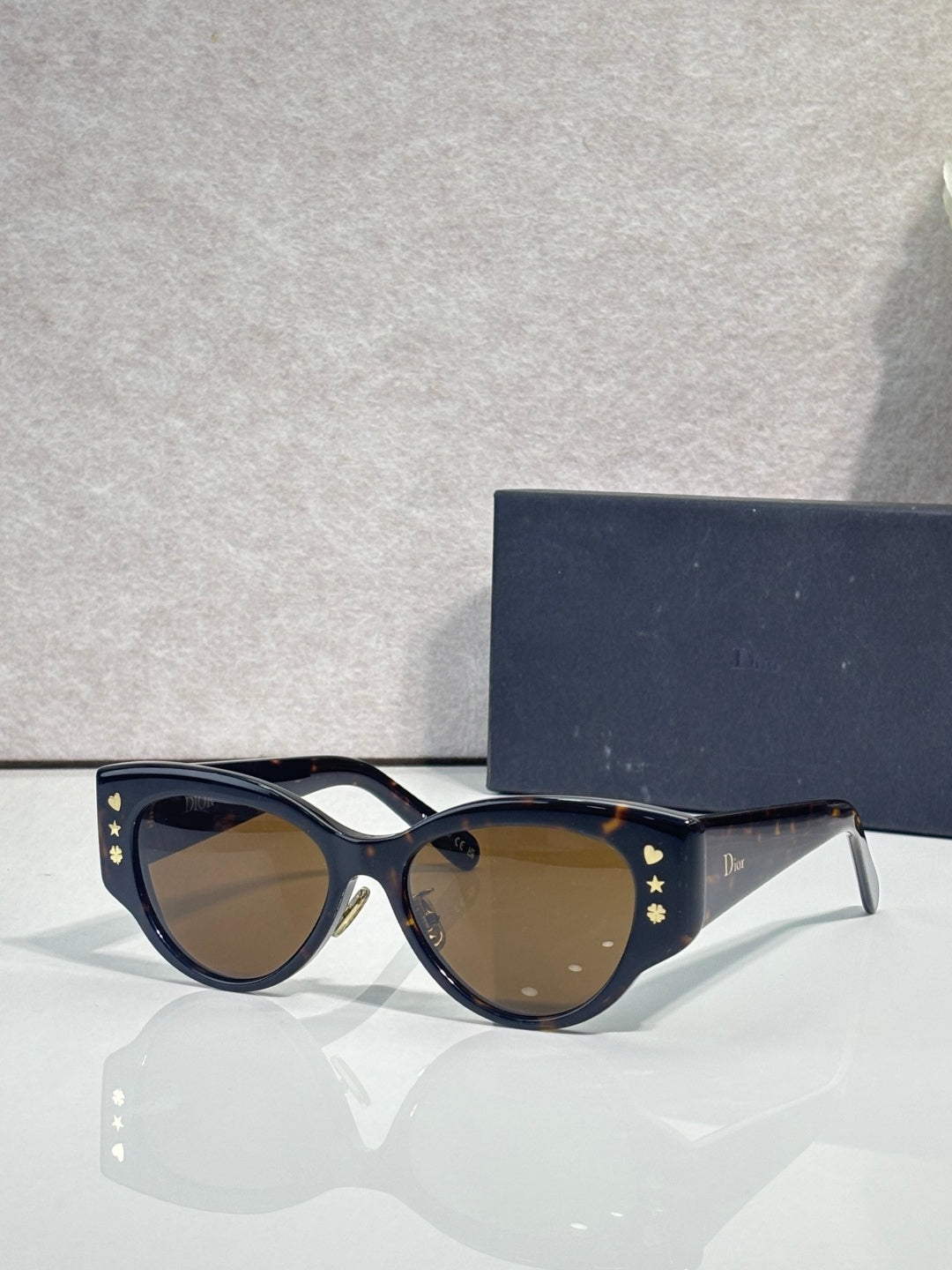Sunglasses with dark blue cat-eye frames, gold star accents, and tinted lenses