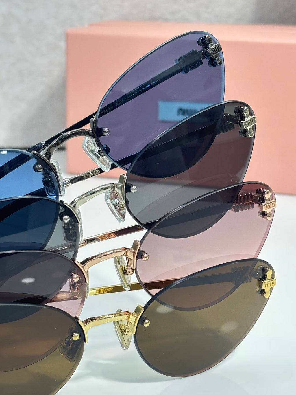 Sunglasses assortment with mixed frames and tinted lenses beside a pink box