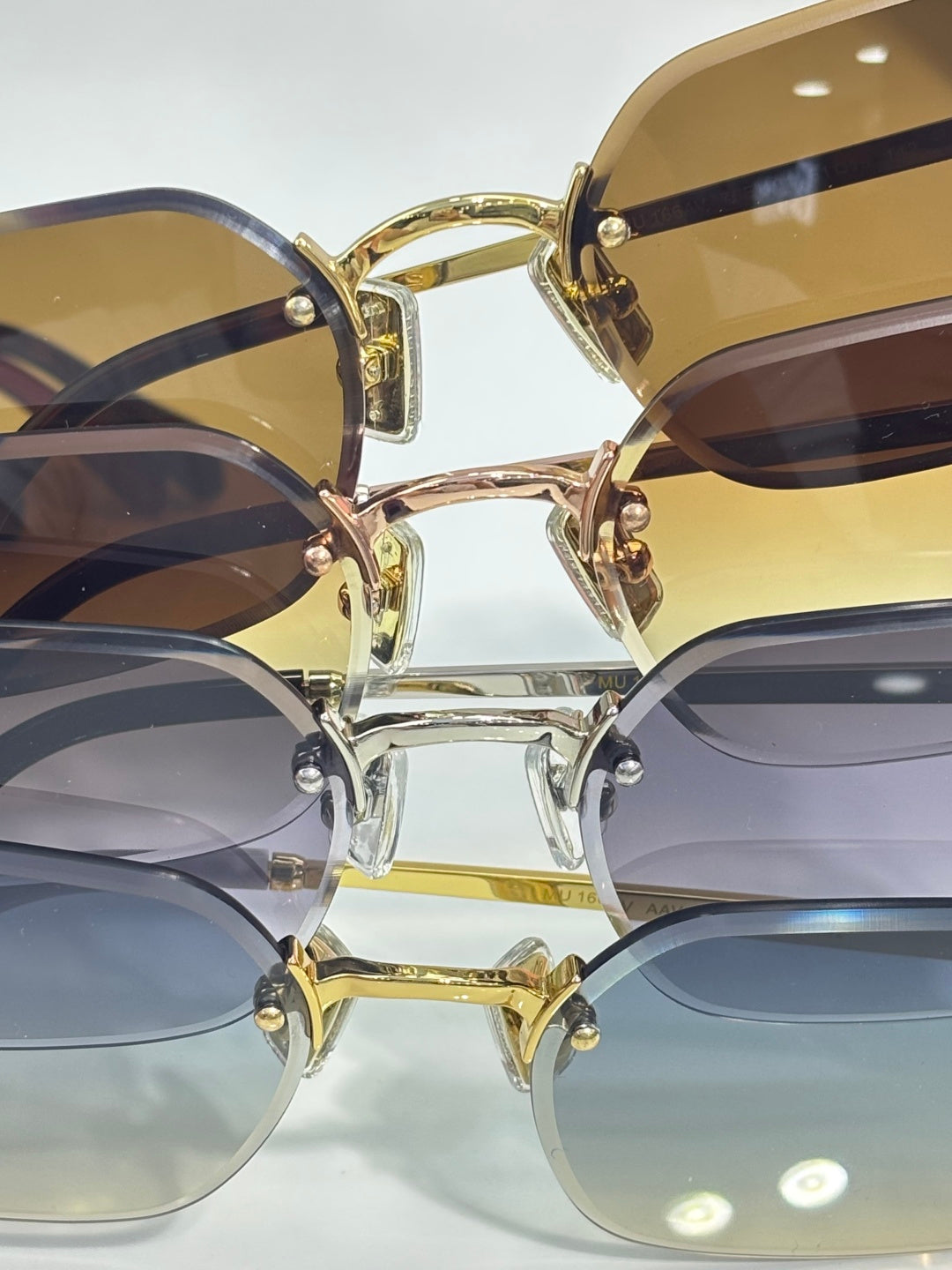 Close-up: stacked sunglasses with gold frames and tinted lenses