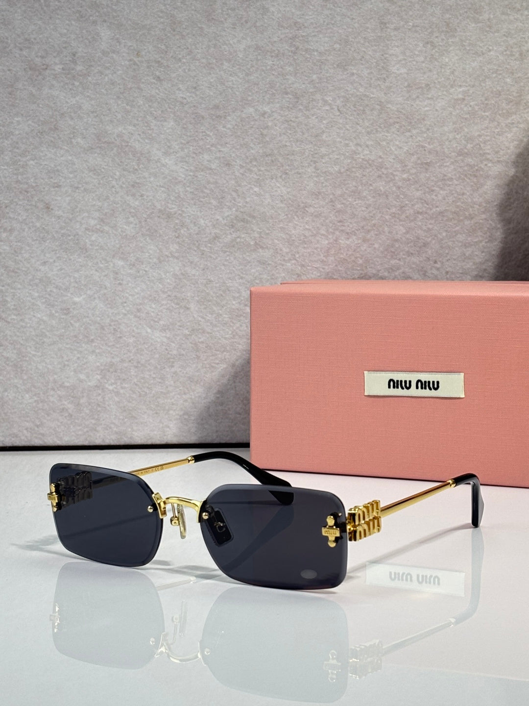 Sunglasses with dark lenses, gold metal frame, maroon detail on arms