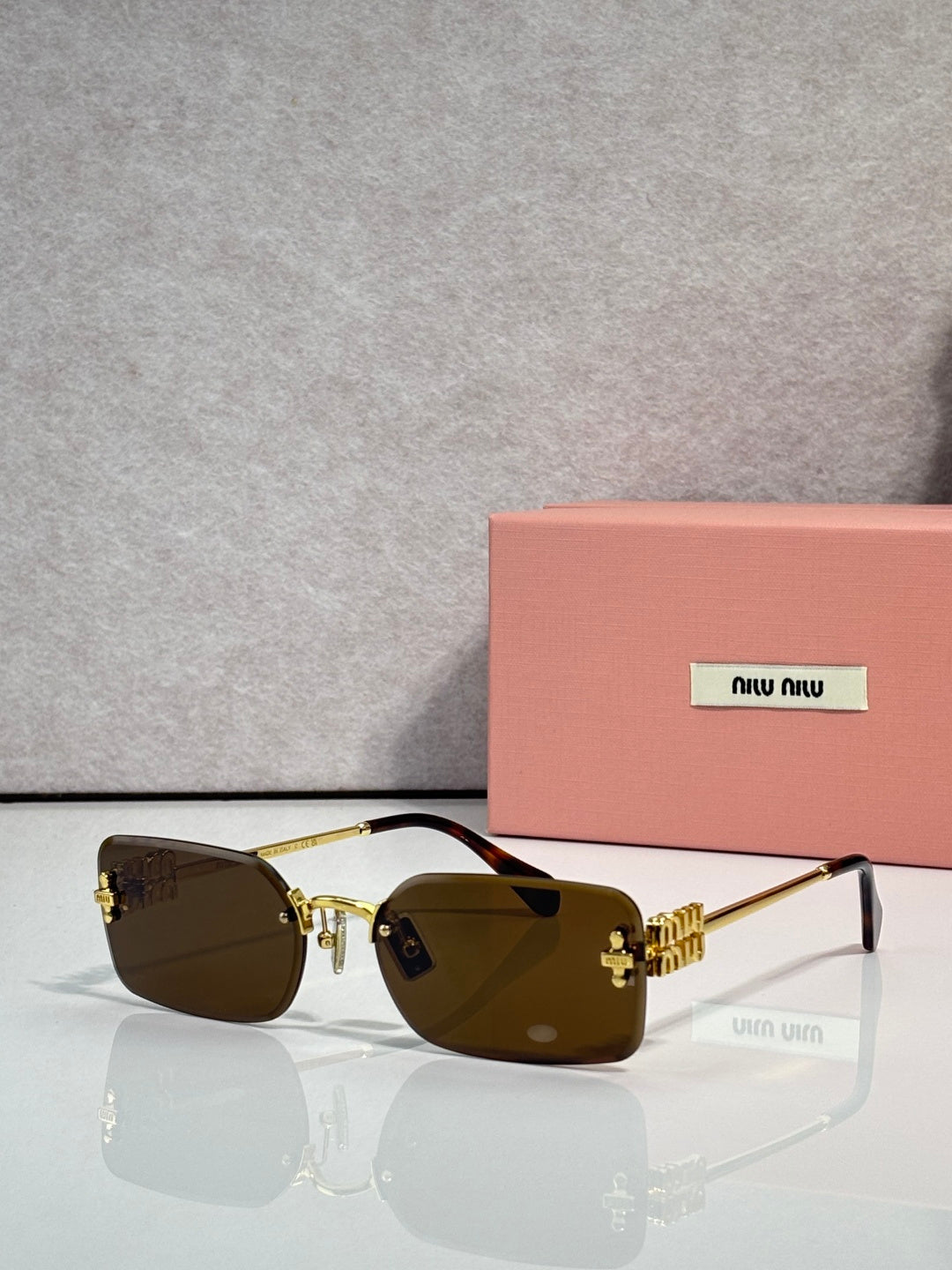 Sunglasses with amber-brown lenses, gold frame, maroon detail on arms