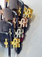 Close-up: gold and silver temple hinges and logo plates on sunglasses