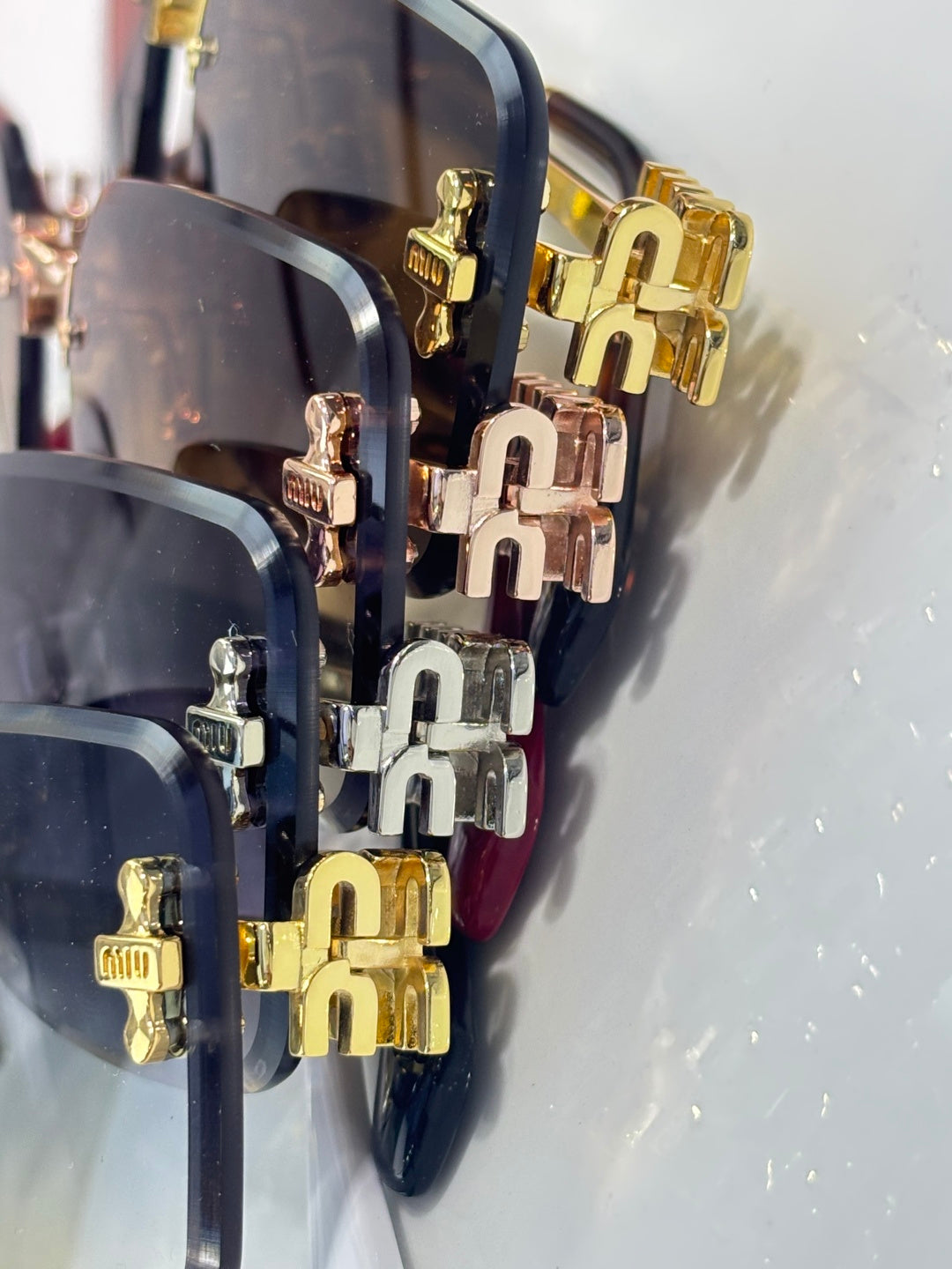 Close-up: gold and silver temple hinges and logo plates on sunglasses