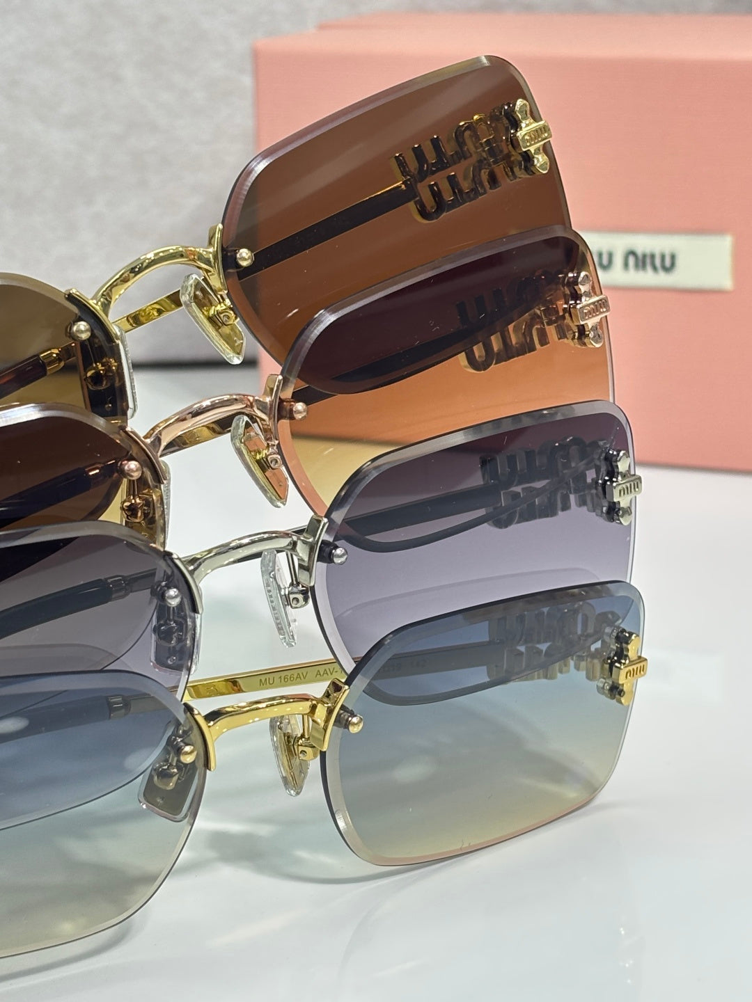 Stacked sunglasses with gold frames and brown, blue, and dark lenses