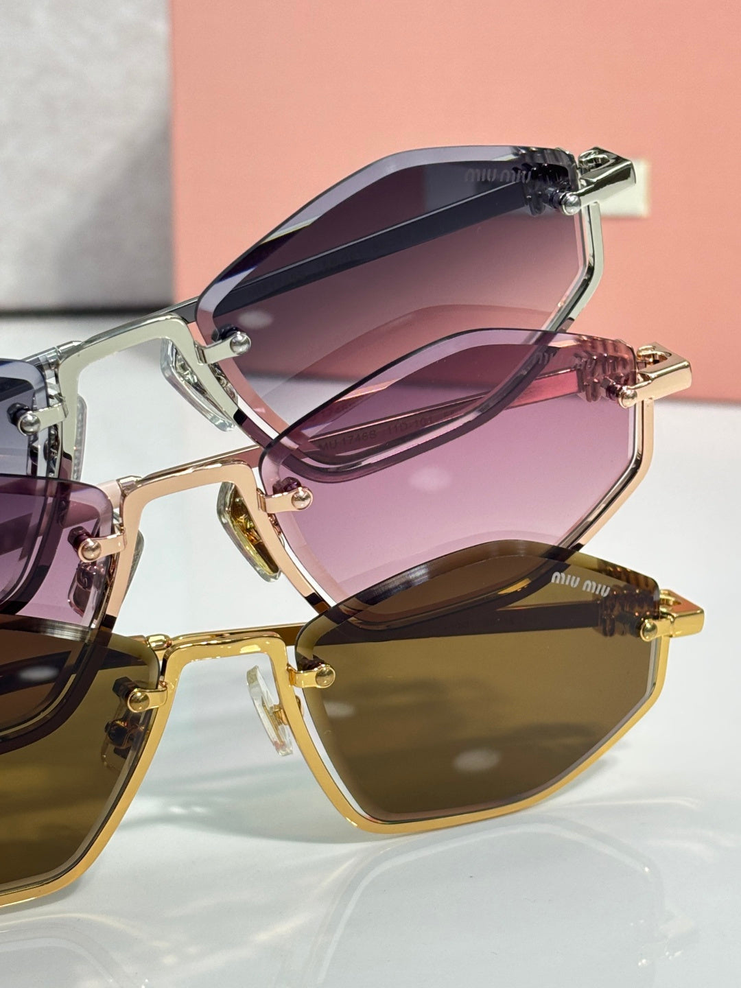 Close-up of stacked sunglasses frames with purple lenses and gold-tone hardware.