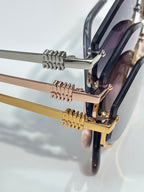 Close-up of gold-tone sunglasses hinges and metal arms with dark lenses.
