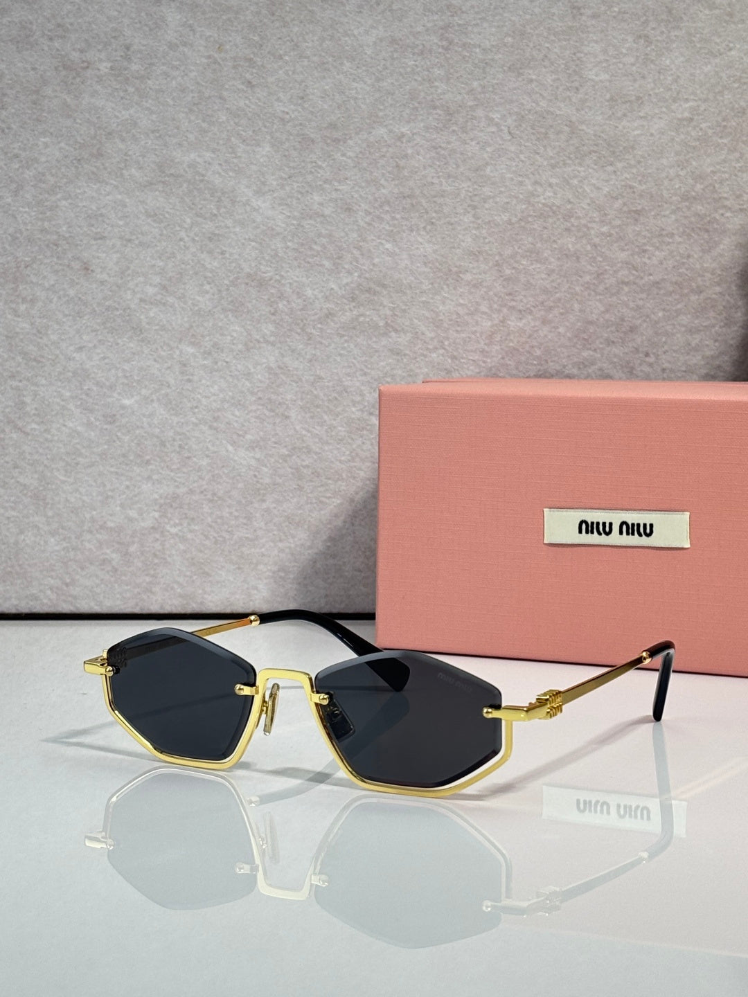 Gold-tone sunglasses with dark blue lenses and black arms, rectangular cat-eye style.