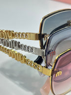 MiuMiu sunglasses close-up: gold and silver chain-link temple with metal frame edge.