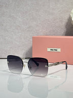 Sunglasses with gradient dark lenses, gold frame and chain temples, black ear tips.
