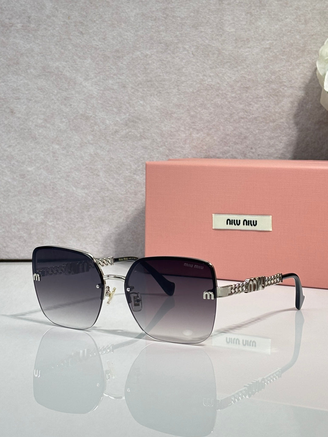 Sunglasses with gradient dark lenses, gold frame and chain temples, black ear tips.