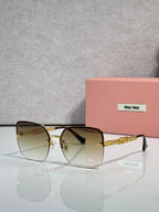 Sunglasses with gradient amber lenses, gold frame and chain temples, black ear tips.