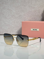 Sunglasses with amber-tinted lenses, gold frame and chain temples, black ear tips.