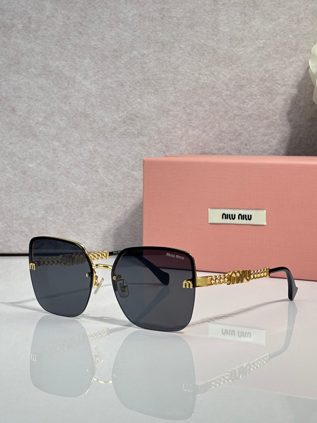 Sunglasses with dark blue lenses, gold frame and chain temples, black ear tips.