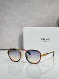 Round sunglasses with gold frame, dark lenses, and tortoise red temple accents