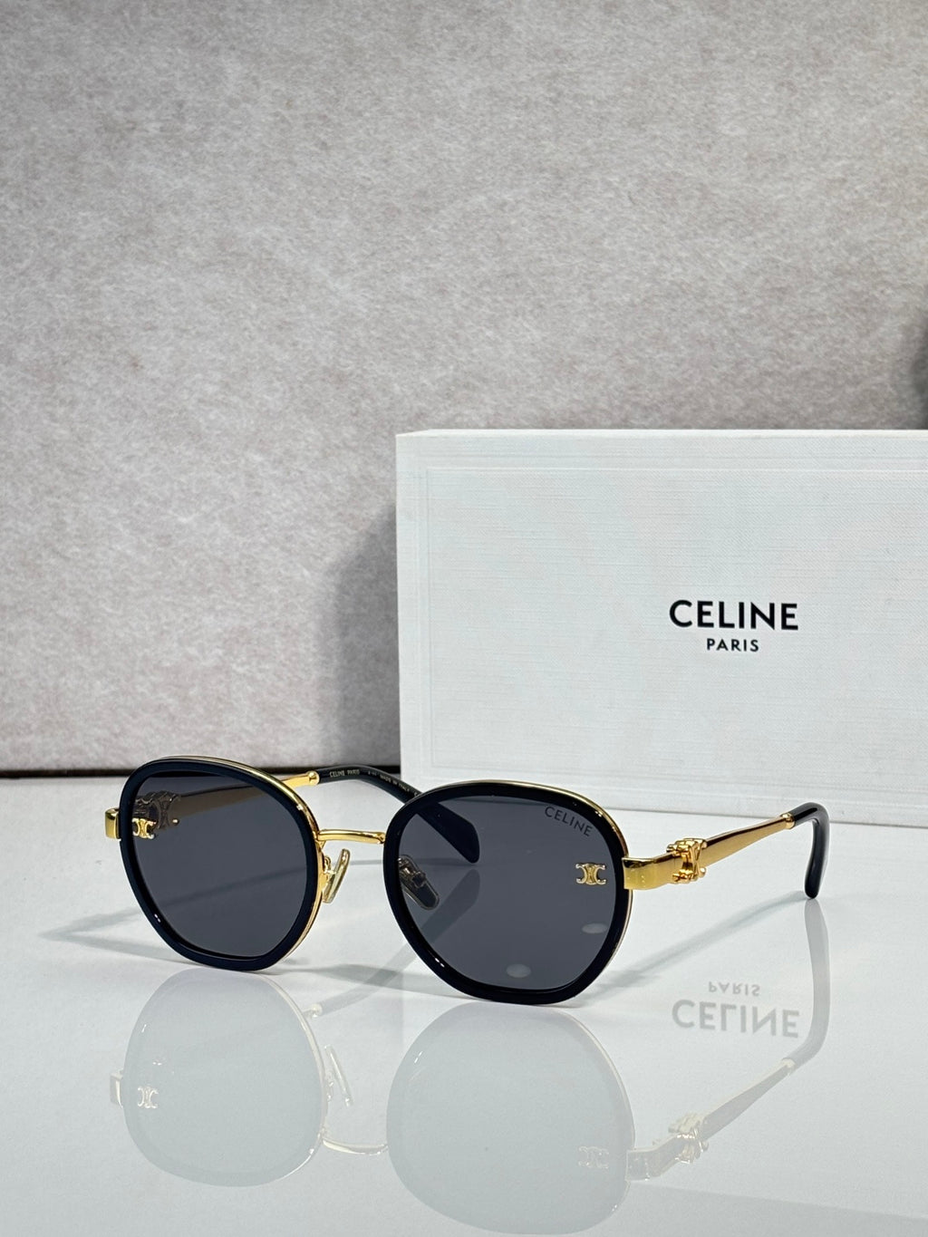 Round sunglasses with dark navy frame and gold-tone rims, dark lenses