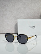 Round sunglasses with dark navy frame and gold-tone rims, dark lenses