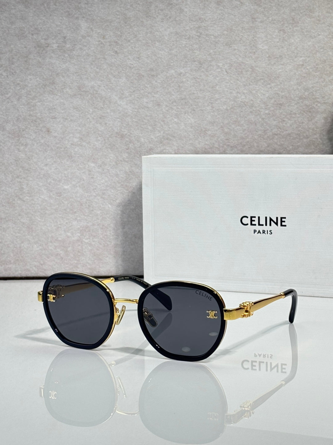 Round sunglasses with dark navy frame and gold-tone rims, dark lenses
