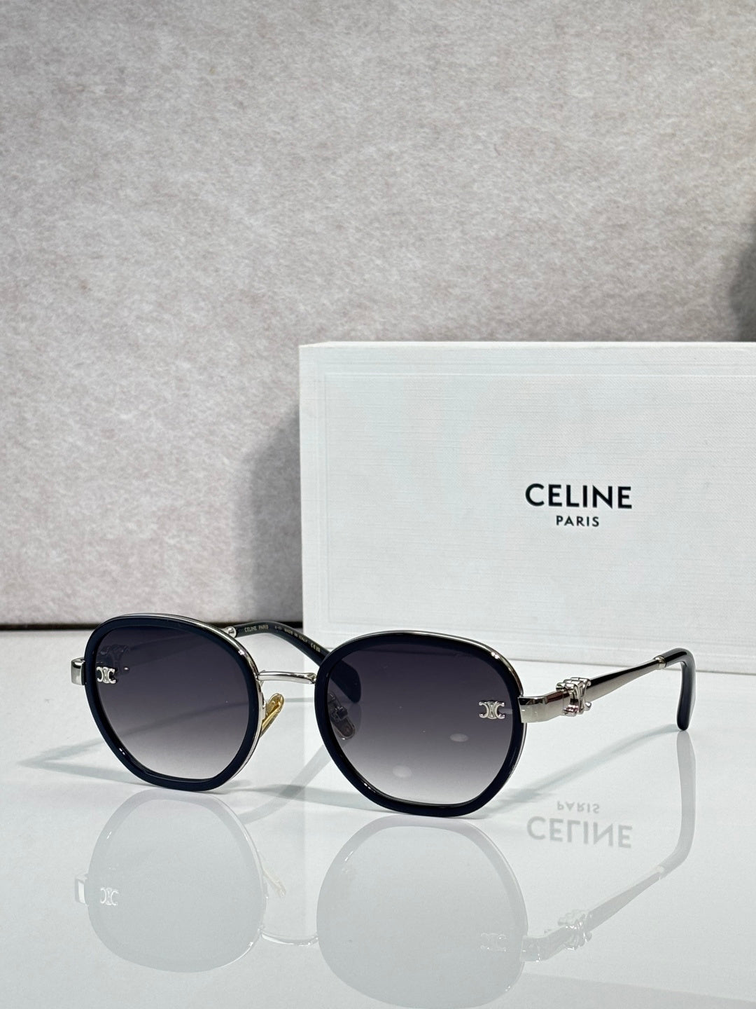 Round sunglasses with dark blue frame and dark lenses, gold-tone hinges and bridge