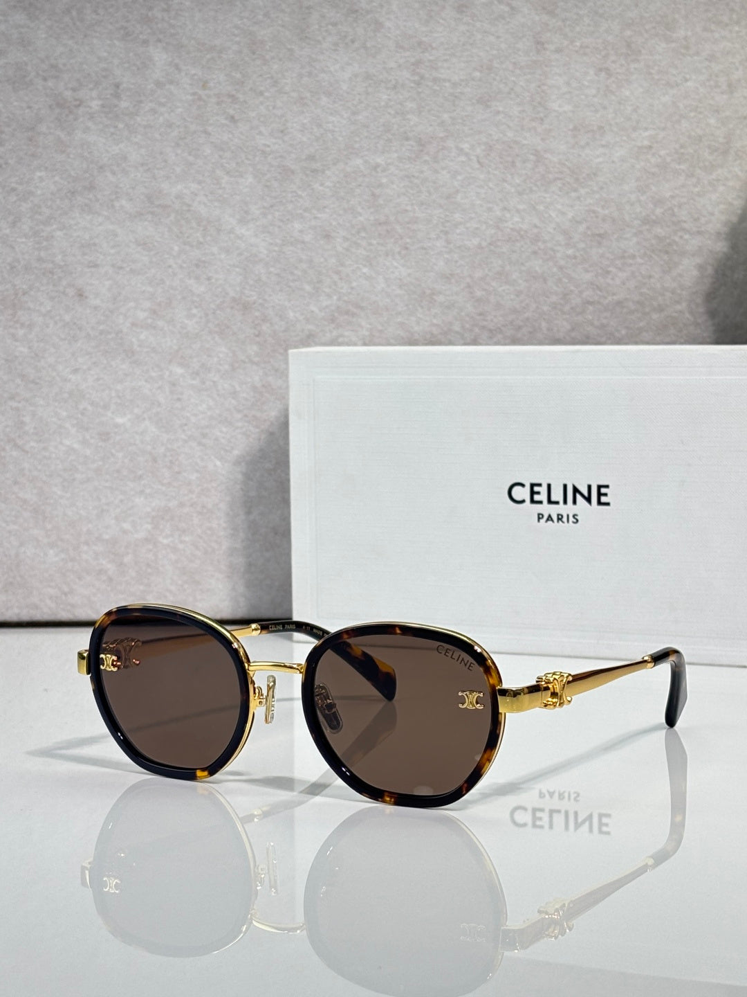 Round sunglasses with gold-tone frame, dark brown lenses, and gold hinges