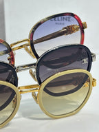 Stacked round sunglasses with gold and red-rim frames and dark tinted lenses