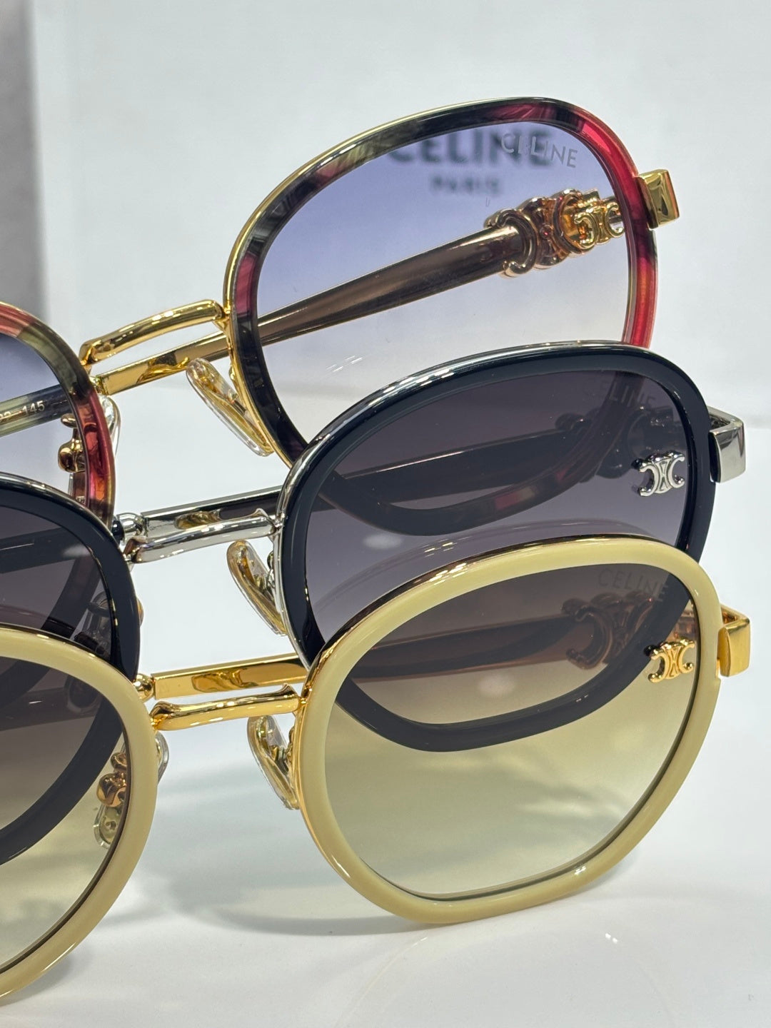 Stacked round sunglasses with gold and red-rim frames and dark tinted lenses