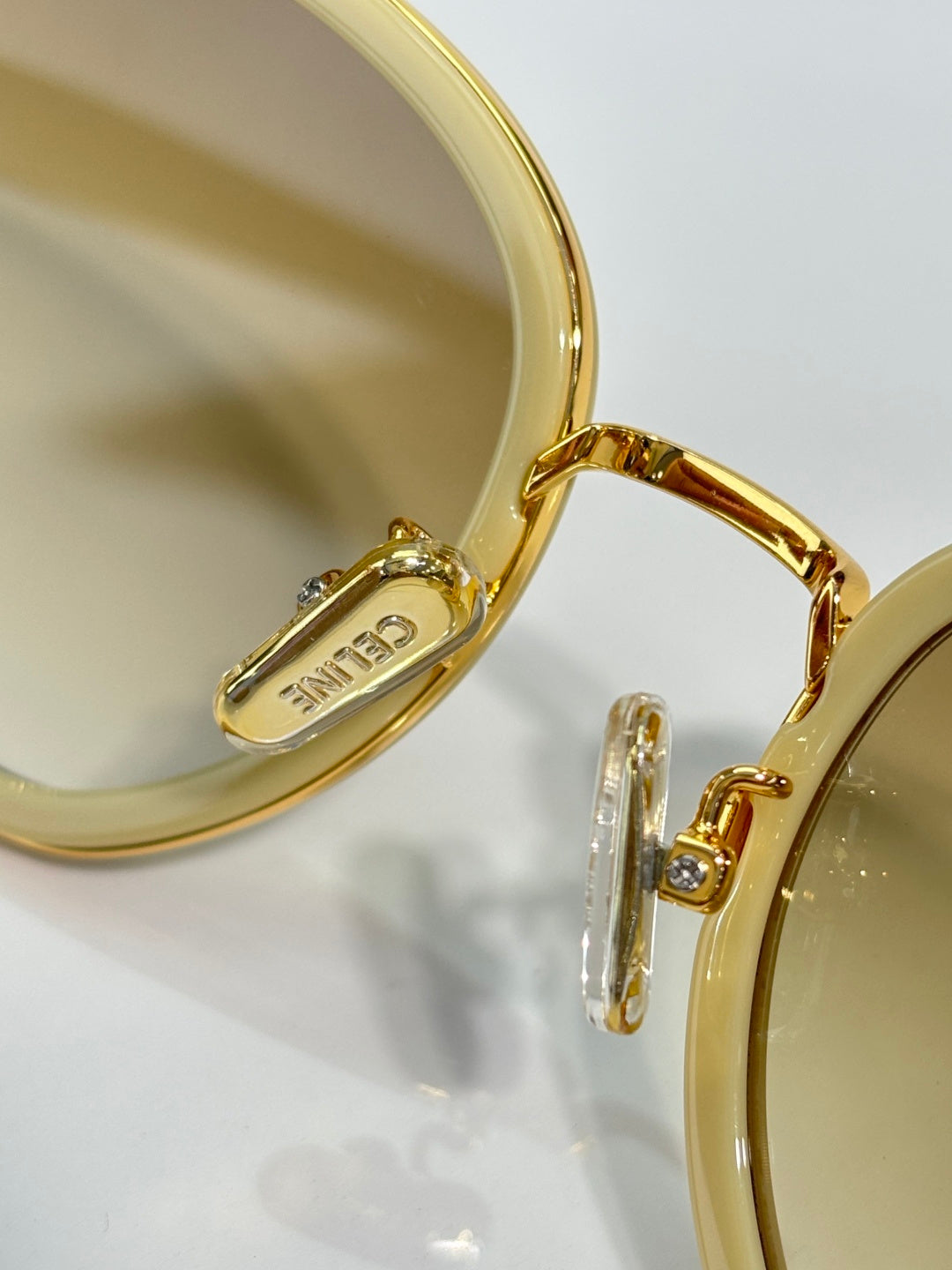 Close-up of gold sunglass temple with engraved logo on the earpiece