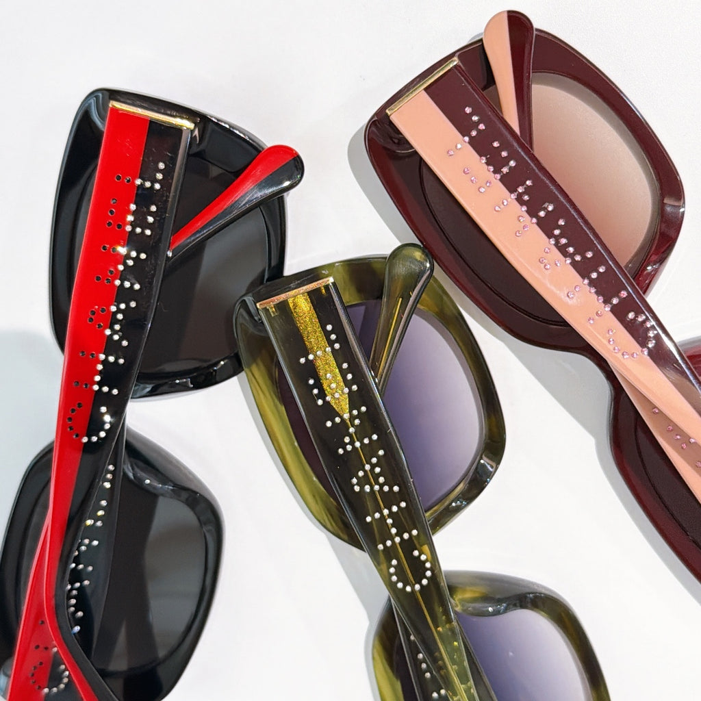Multiple square sunglasses in red, green, and burgundy with logo temples