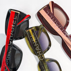 Multiple square sunglasses in red, green, and burgundy with logo temples