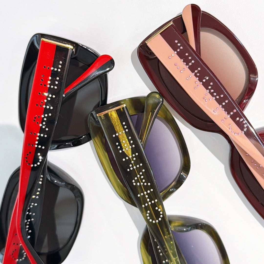 Multiple square sunglasses in red, green, and burgundy with logo temples