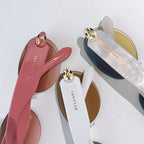 Sunglasses close-up showing pink and white temples with gold emblems