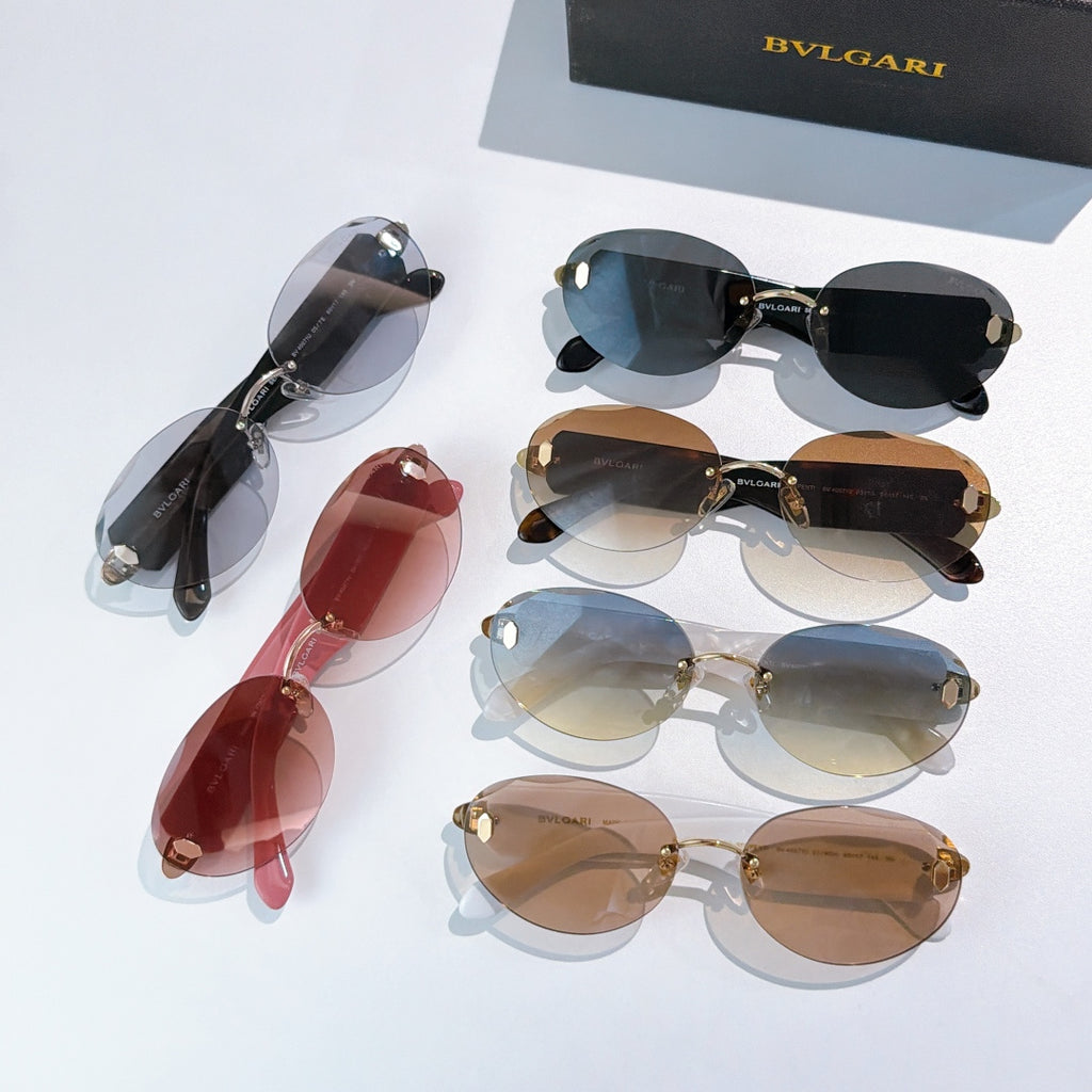 Assorted sunglasses with dark, red, and brown lenses, gold-tone frames