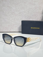 Sunglasses with dark blue frames, light-tinted lenses, and gold B emblem