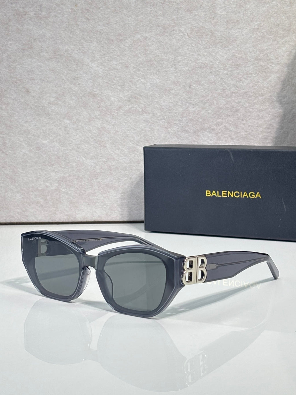 Sunglasses with dark blue frames, gray lenses, and gold B emblem