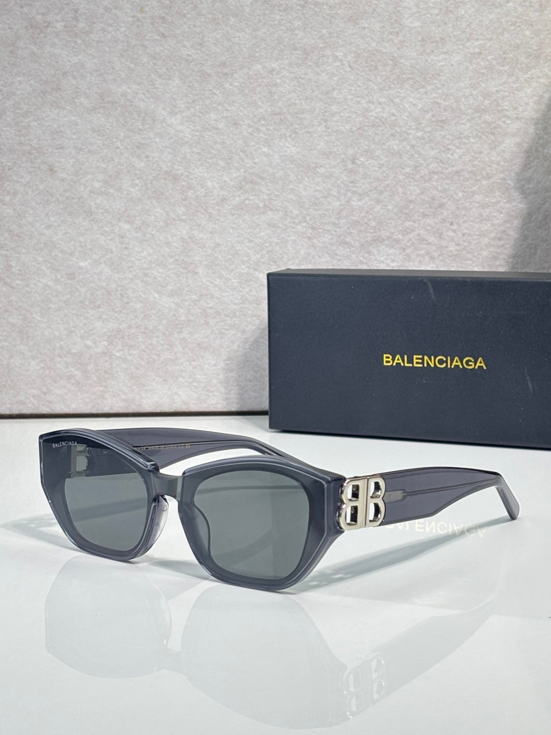 Sunglasses with dark blue frames, gray lenses, and gold B emblem
