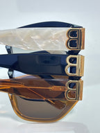 Sunglasses close-up with gold B emblem on temple and tinted lenses