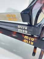 Sunglasses temple closeup with 'miu miu' lettering on dark acetate