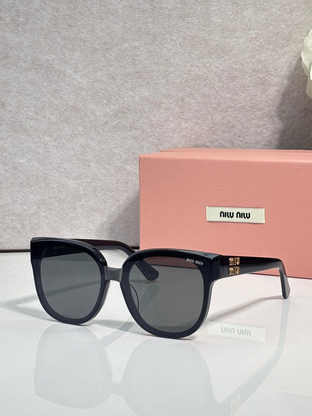 Sunglasses with dark frames and dark-tinted lenses, curved bridge and logo detail