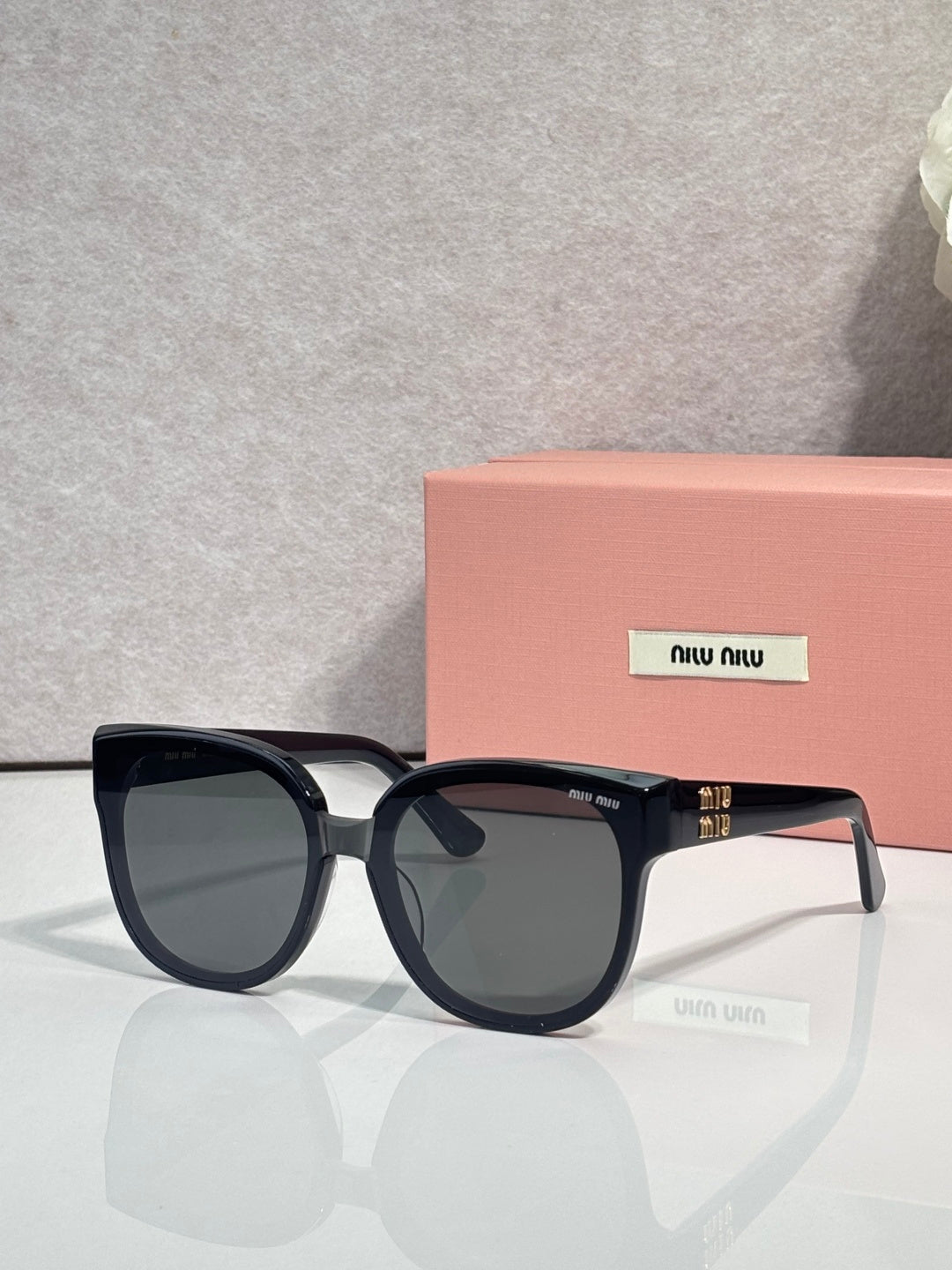 Sunglasses with dark frames and dark-tinted lenses, curved bridge and logo detail