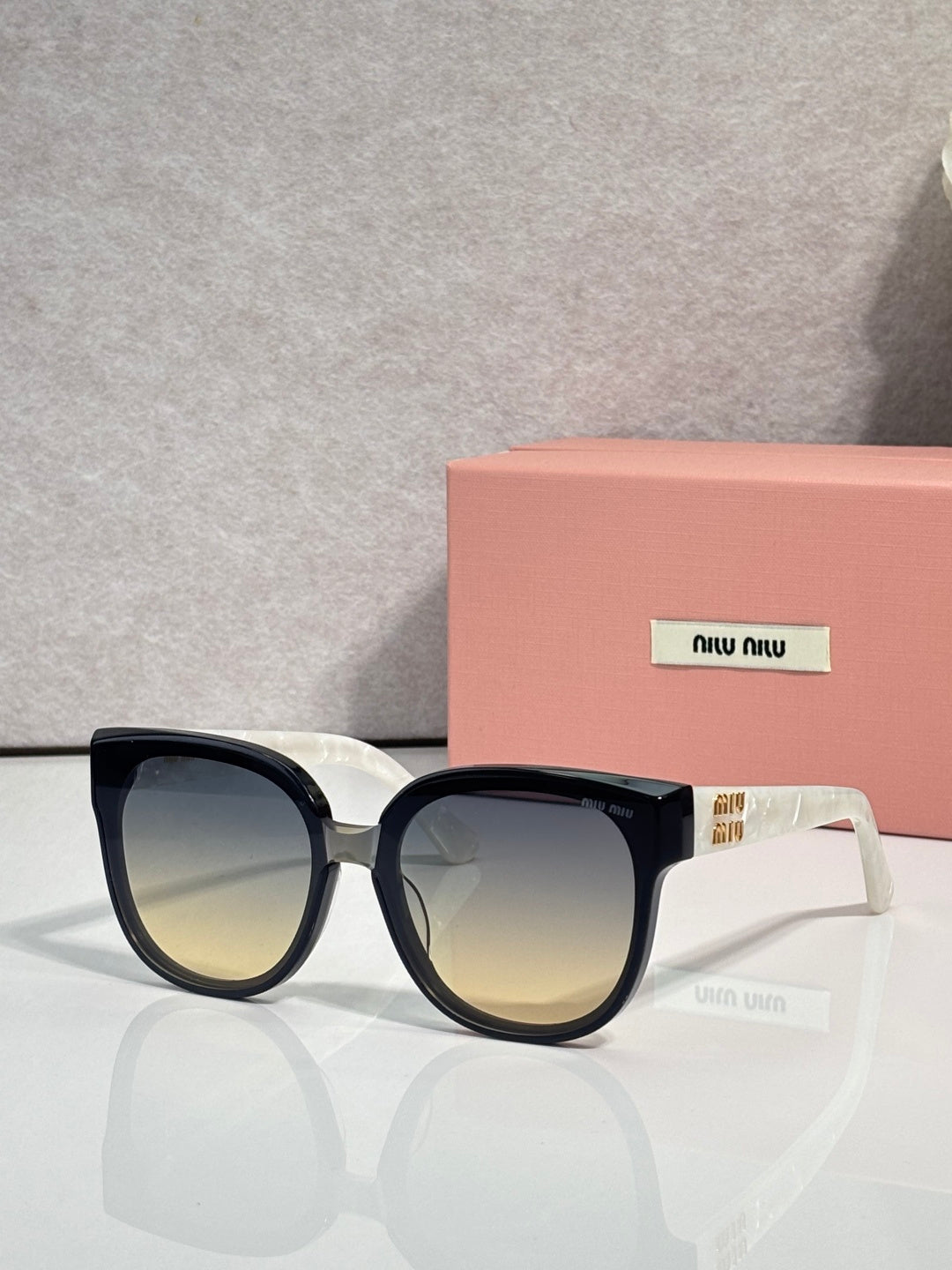 Sunglasses with dark frames and blue-tinted lenses, gold-tone accent on the temple