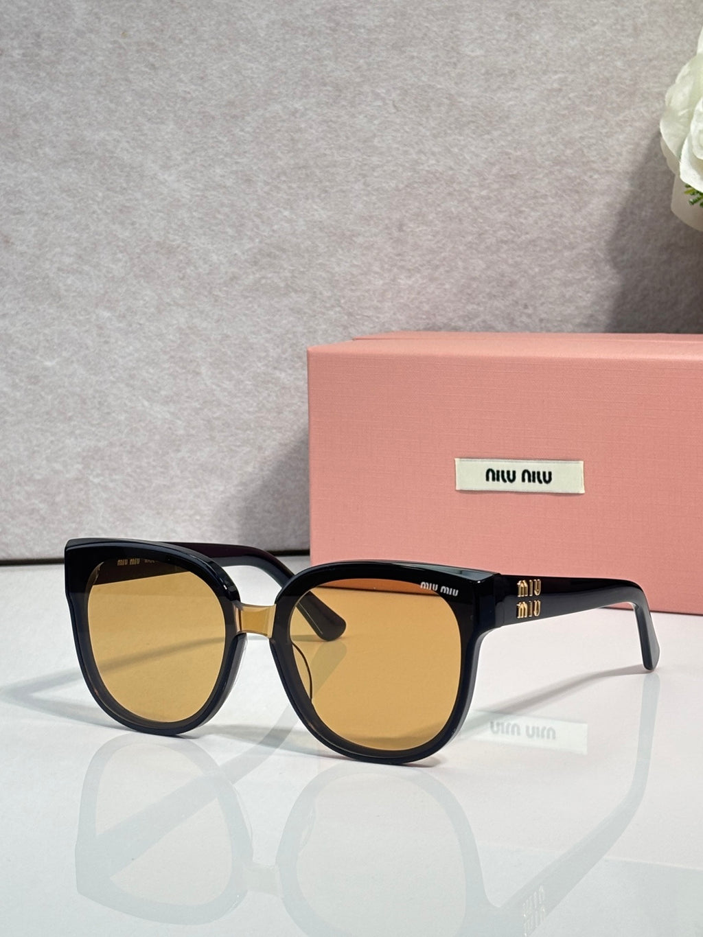 Sunglasses with dark frames and amber-tinted lenses, gold-tone accent at the temple