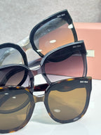Stacked sunglasses with dark frames and tinted lenses, close-up view