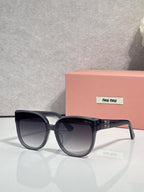 Sunglasses with dark frames and gray tinted lenses, rounded shape with clear accents