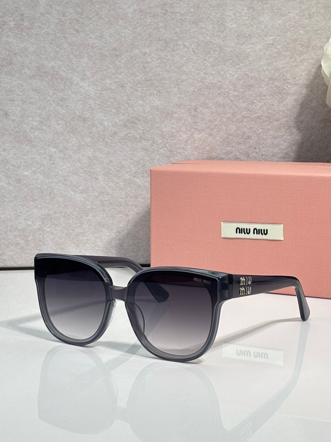Sunglasses with dark frames and gray tinted lenses, rounded shape with clear accents