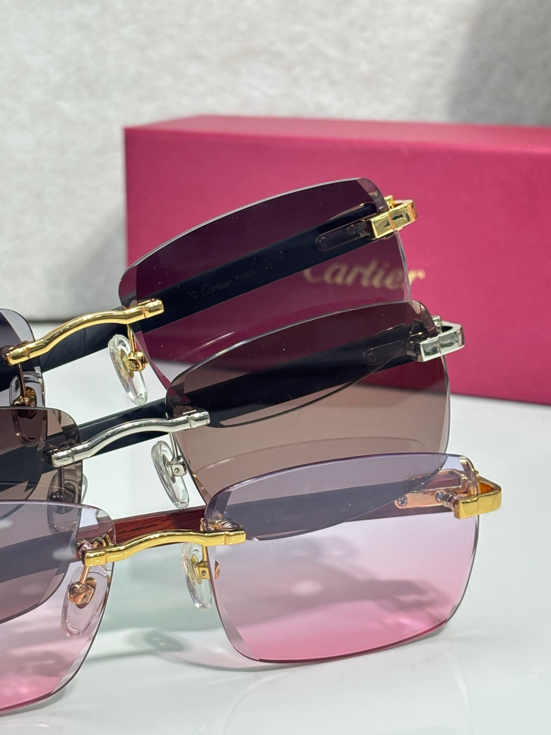 Cartier glasses close-up: gold hinges on rectangular frames with pink-tinted lenses