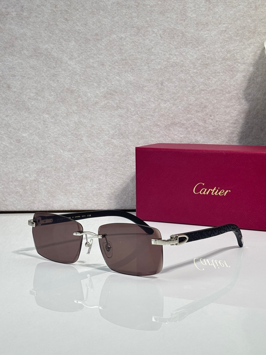Cartier glasses with rectangular dark frames and gold accents; brown-tinted lenses