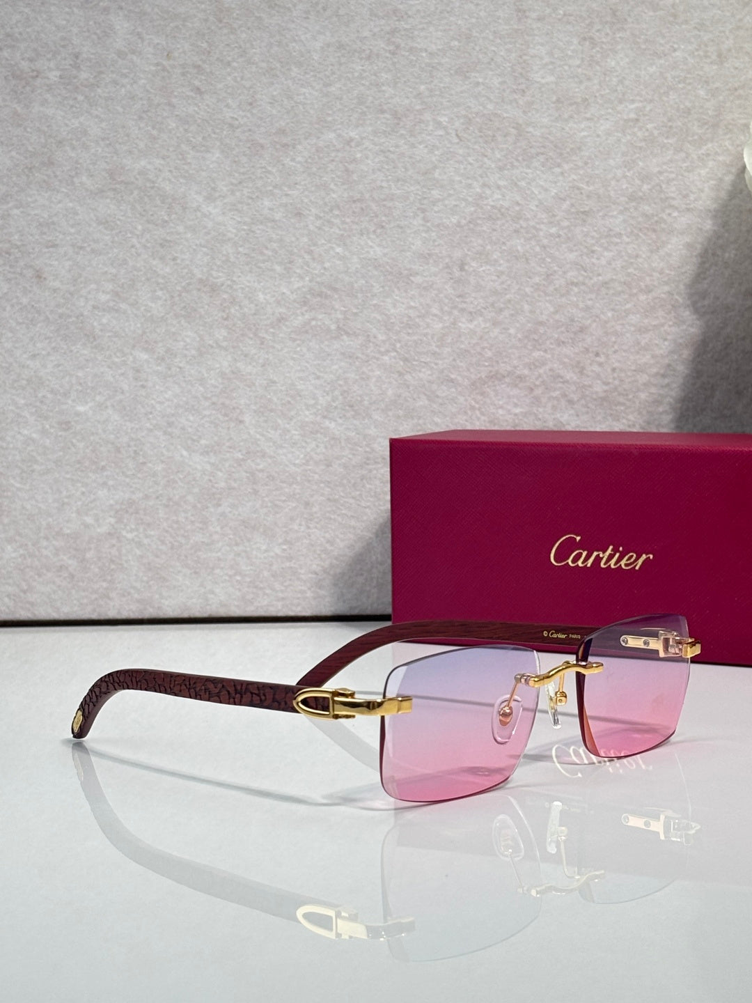 Cartier glasses with rectangular frames, burgundy temples, gold accents; pink-tinted lenses