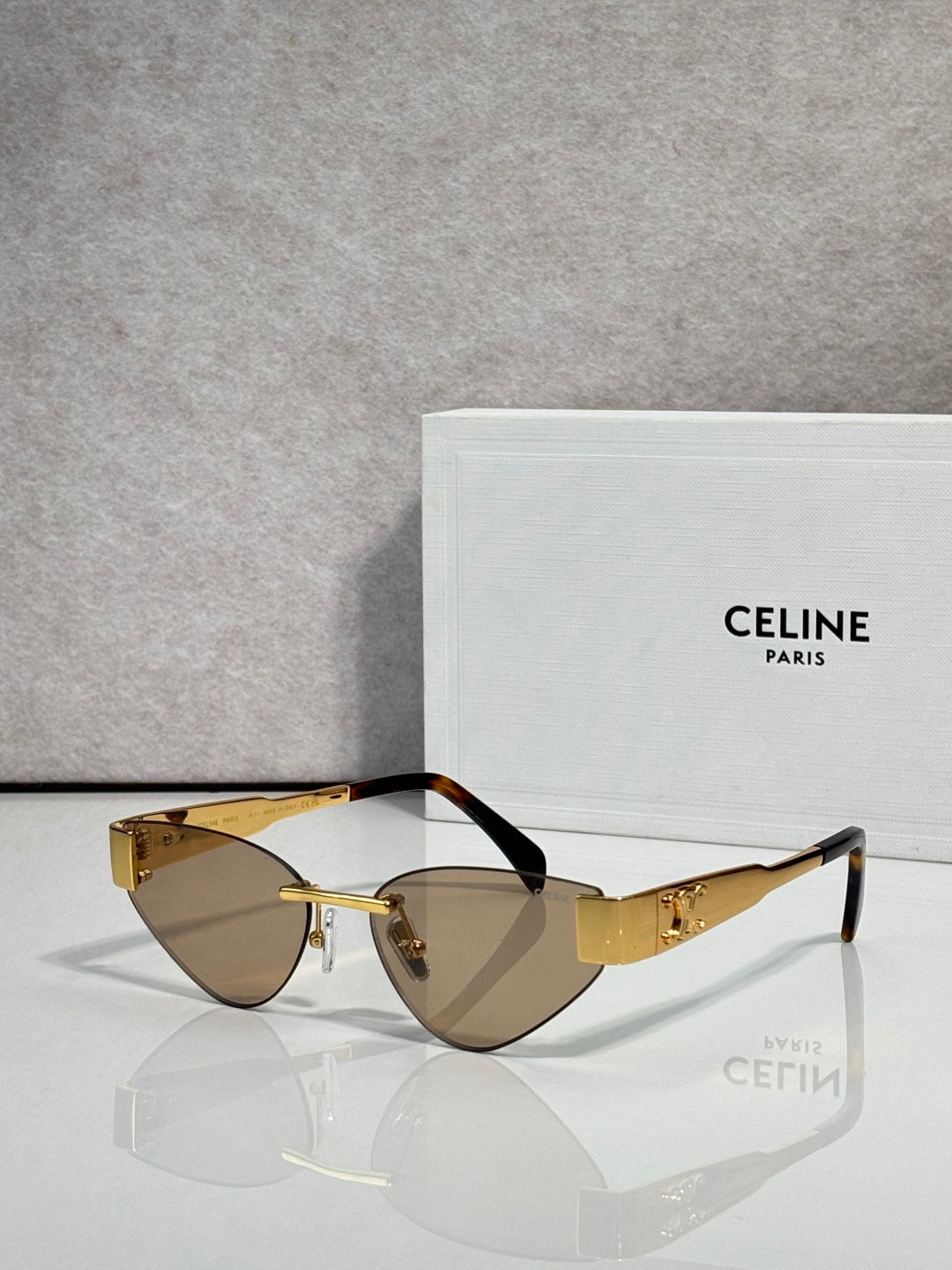 Celine glasses with gold frame and dark brown lenses, front view with black temples