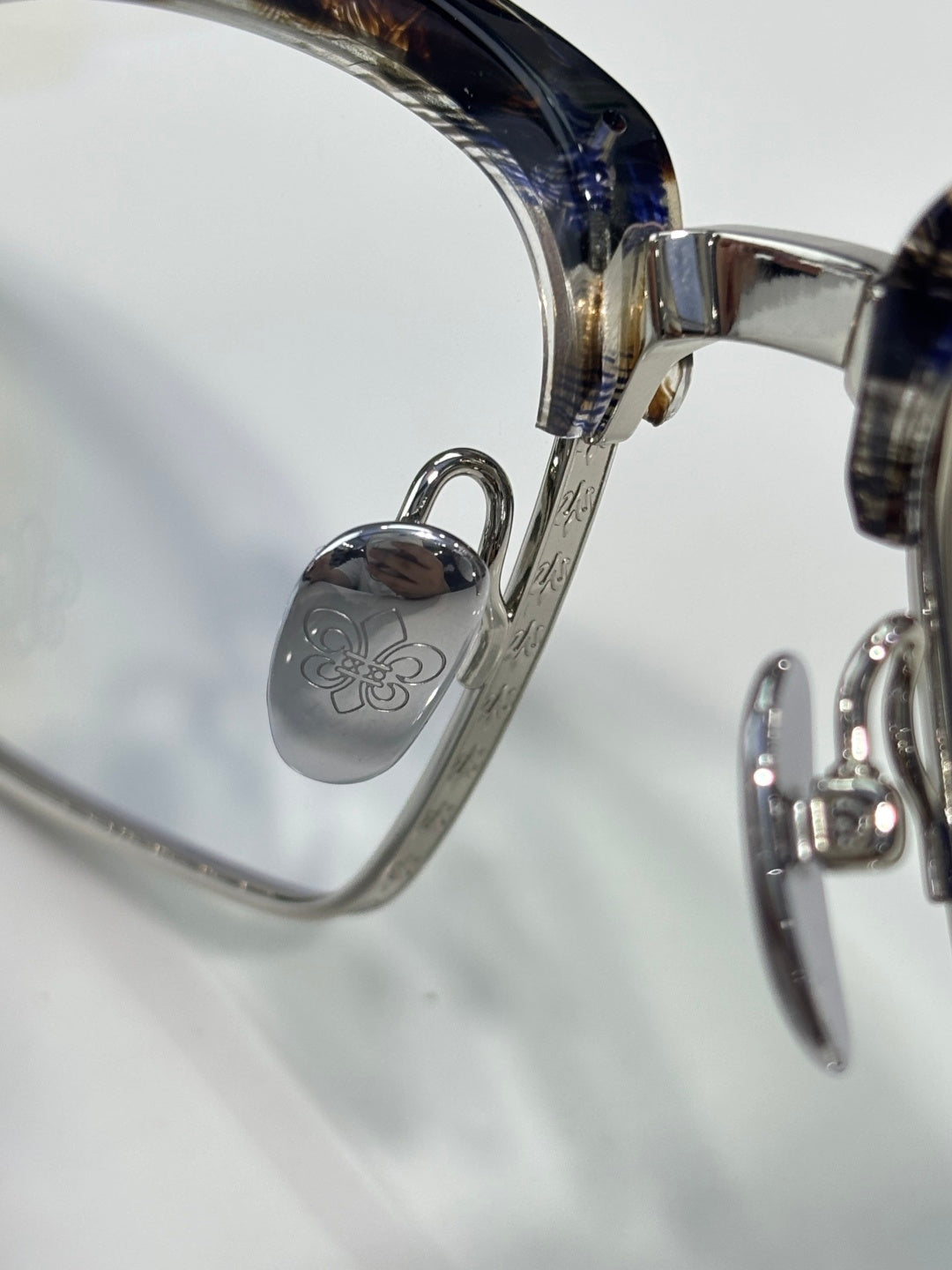 Eyeglass frame hinge with engraved logo and oval metal detailing