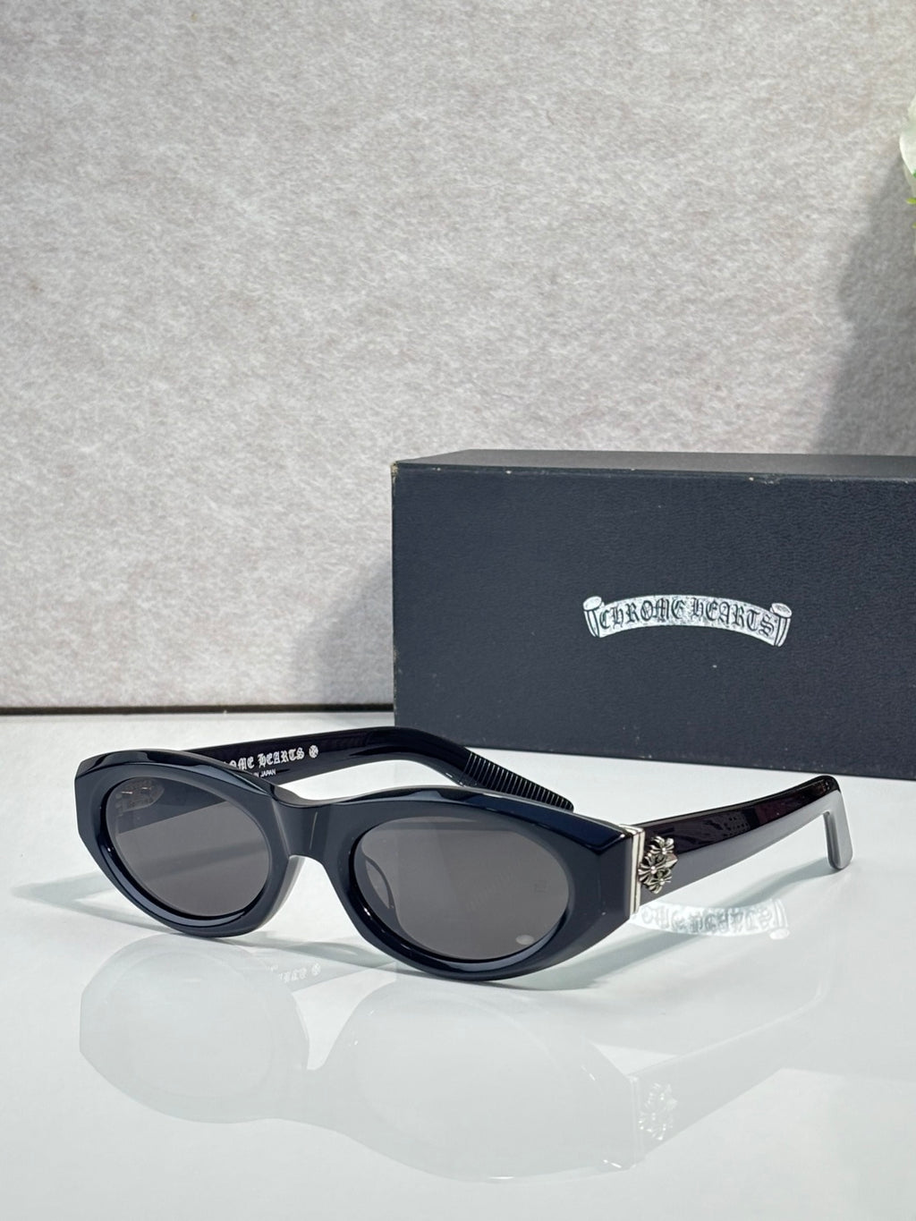 Cat-eye glasses with dark frame and tinted lenses, styled with metallic side hardware