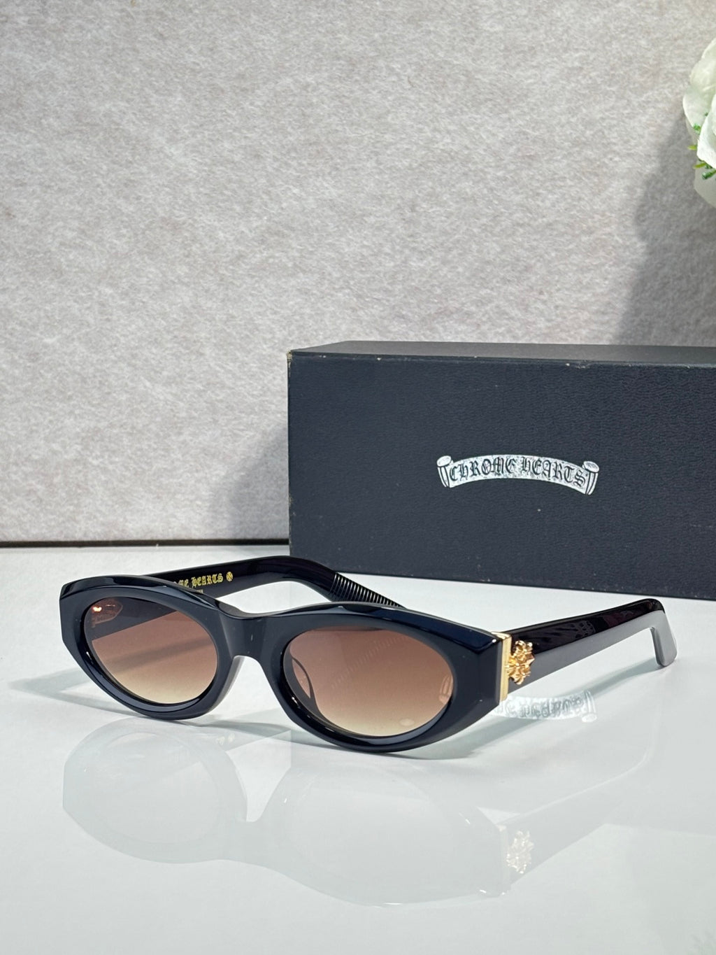 Cat-eye glasses with black frame and brown-tinted lenses, with gold-toned side accents